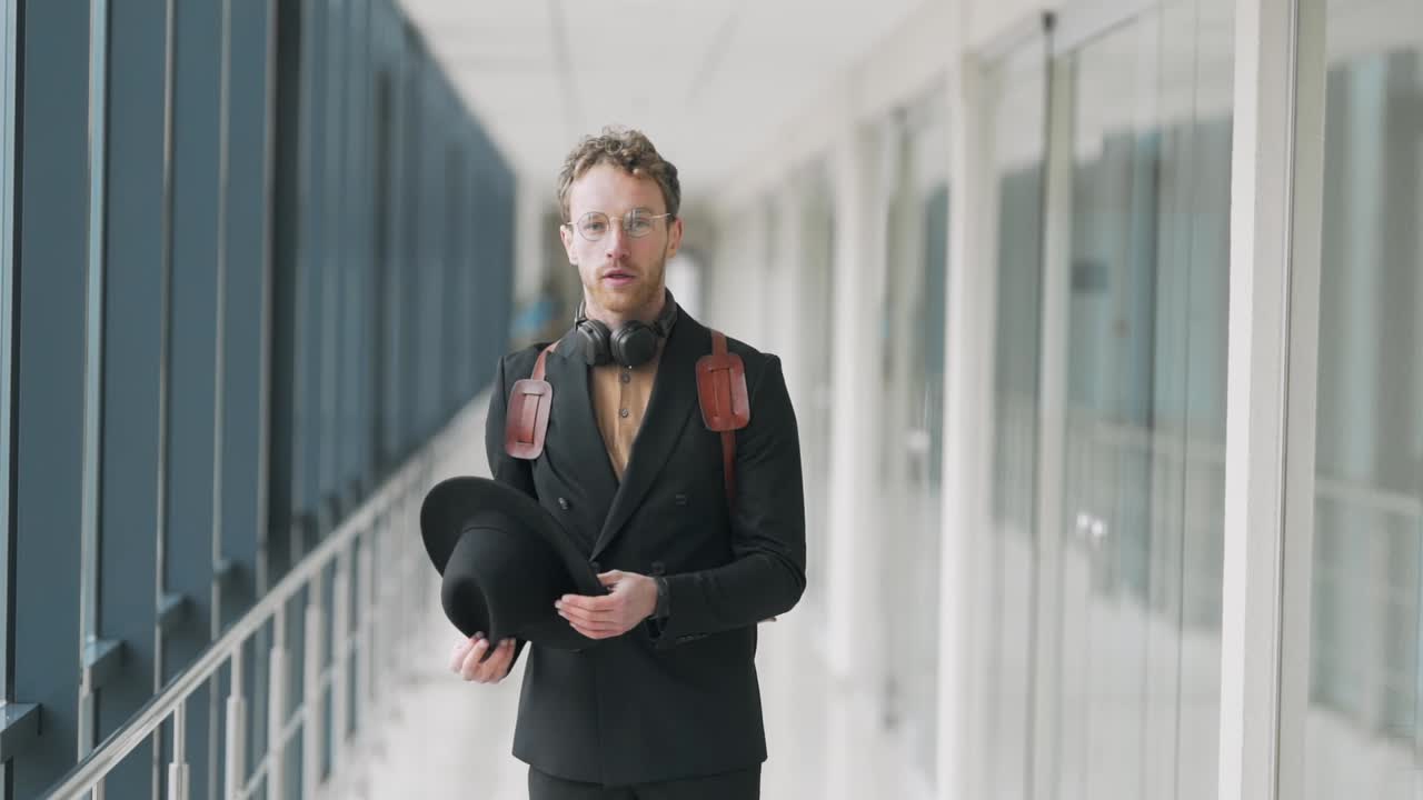 Stylish young man puts on a hat in the hallway