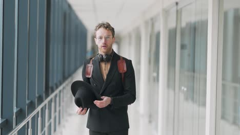 stylish young man puts on a hat in the hallway