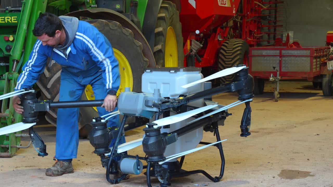 Fazendeiro dobra cuidadosamente os braços e hélices do drone no celeiro para preparar o transporte para o campo de trigo. Em câmera lenta.