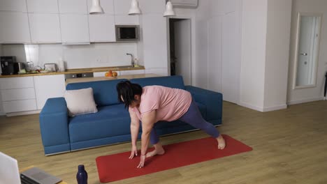 Übergewichtige-Frau-Führt-Zu-Hause-Yoga-Asana-Krieger-Durch