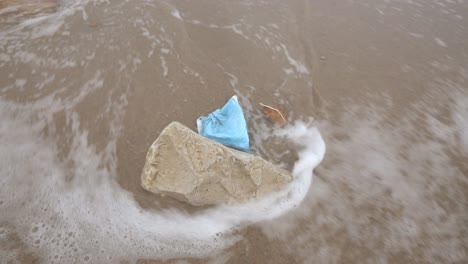 medical mask washed by sea water on beach