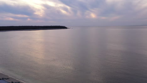 An-aerial-view-over-the-Long-Island-Sound-by-Orient-Point-on-Long-Island,-New-York-during-a-golden-sunset-with-cloudy-skies