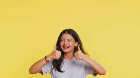 mujer joven mostrando los pulgares hacia arriba y apuntando por encima en el espacio en blanco lugar para su logotipo de publicidad