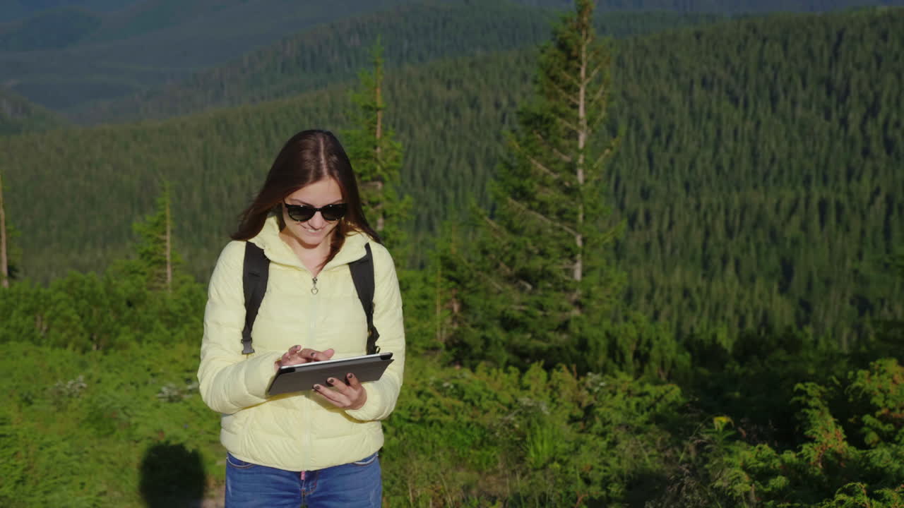 mujer joven disfrutando de un teléfono inteligente en un pintoresco telón de fondo de montañas cubiertas de bosque siempre