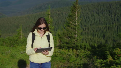 mujer joven disfrutando de un teléfono inteligente en un pintoresco telón de fondo de montañas cubiertas de bosque siempre