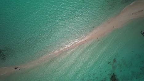 A-sandy-path-surrounded-by-turquoise-water-on-a-sunny-day-in-cayo-de-agua,-aerial-view