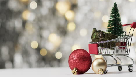 Video-of-shopping-trolley-with-christmas-tree-decorations-and-copy-space-on-fairy-lights-background