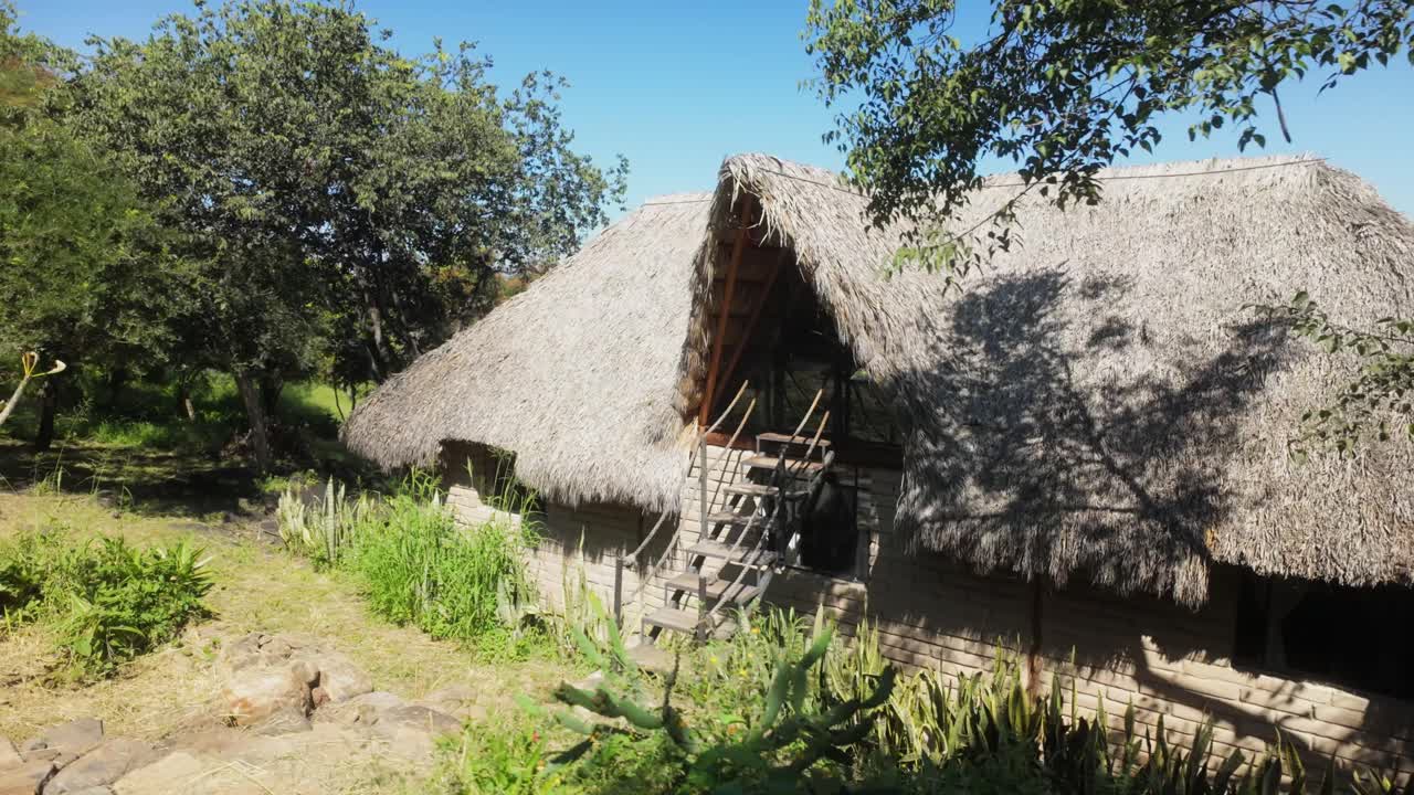 Rustic cob and superadobe house with thatched roof and exterior stairs to terrace at Igloo Kokolo nature retreat