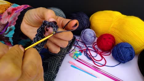 close up shot of woman hand crocheting a bag for laptop or tablet by a hook and using colorful wool