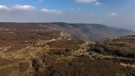 Drone-shot,-two-hikers-on-a-wild-trail,-epic-valley-in-background,-sunny-day