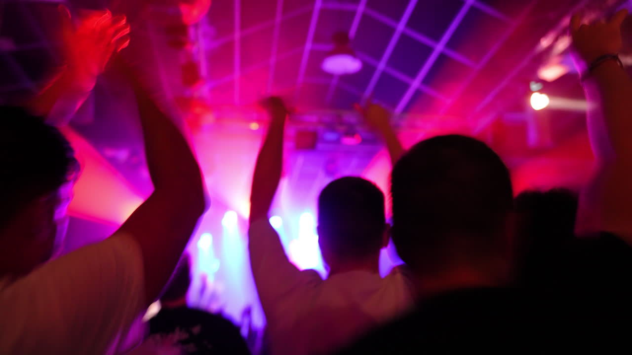 Audience enjoying live music performance with vibrant lights and energetic atmosphere in background
