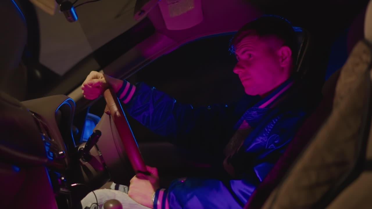 Interior de coche iluminado con luces de neón, hombre blanco agarrando el volante, conductor tenso esperando bajo una luz ambiental azul púrpura, perfil cercano con reflejos en el parabrisas, ambiente noir cinematográfico, resplandor de farolas urbanas