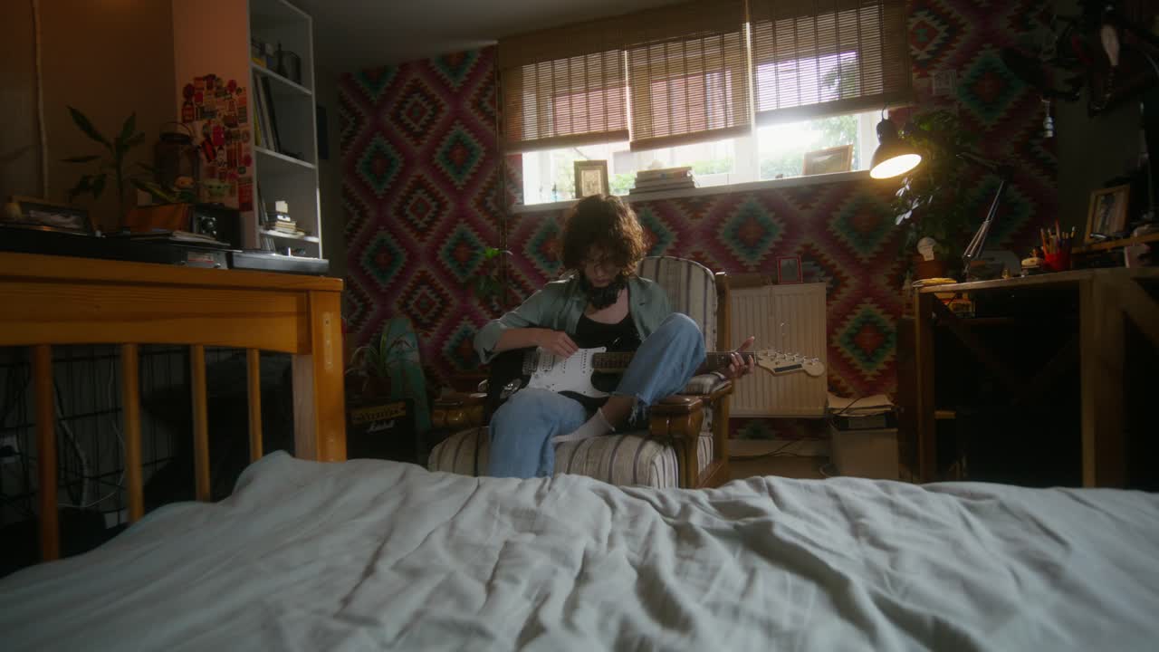 una adolescente tocando la guitarra eléctrica en su habitación