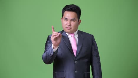 초록색 배경에 젊은 잘생긴 과체중 아시아 사업가
