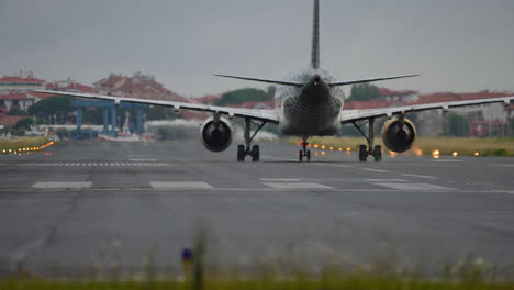 airplane positioned on runway, ready for takeoff, with cloudy sky and airport structures visible in the background, showcasing aviation activity