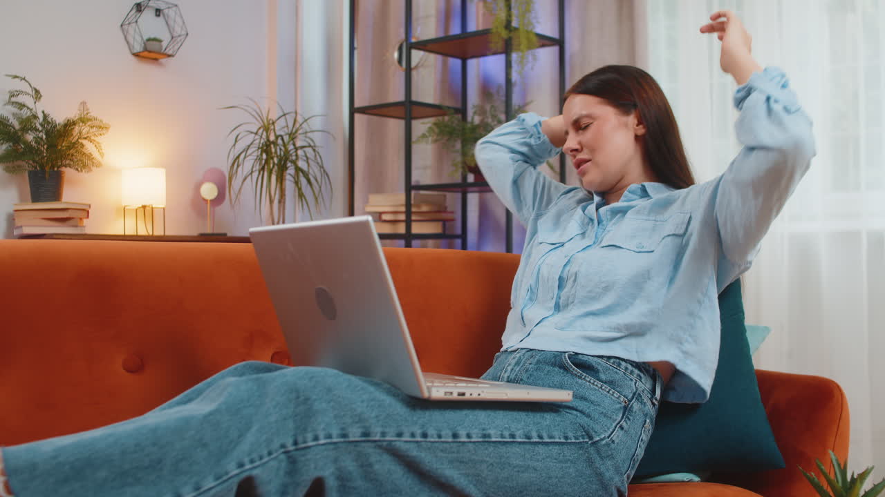joven caucásica molesta usando una computadora portátil que tiene ansiedad y estrés sentada en el sofá en casa