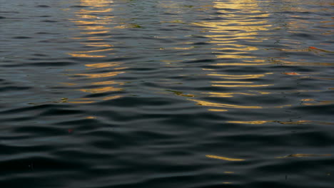 orange and yellow lights reflect smooth rippling dark water