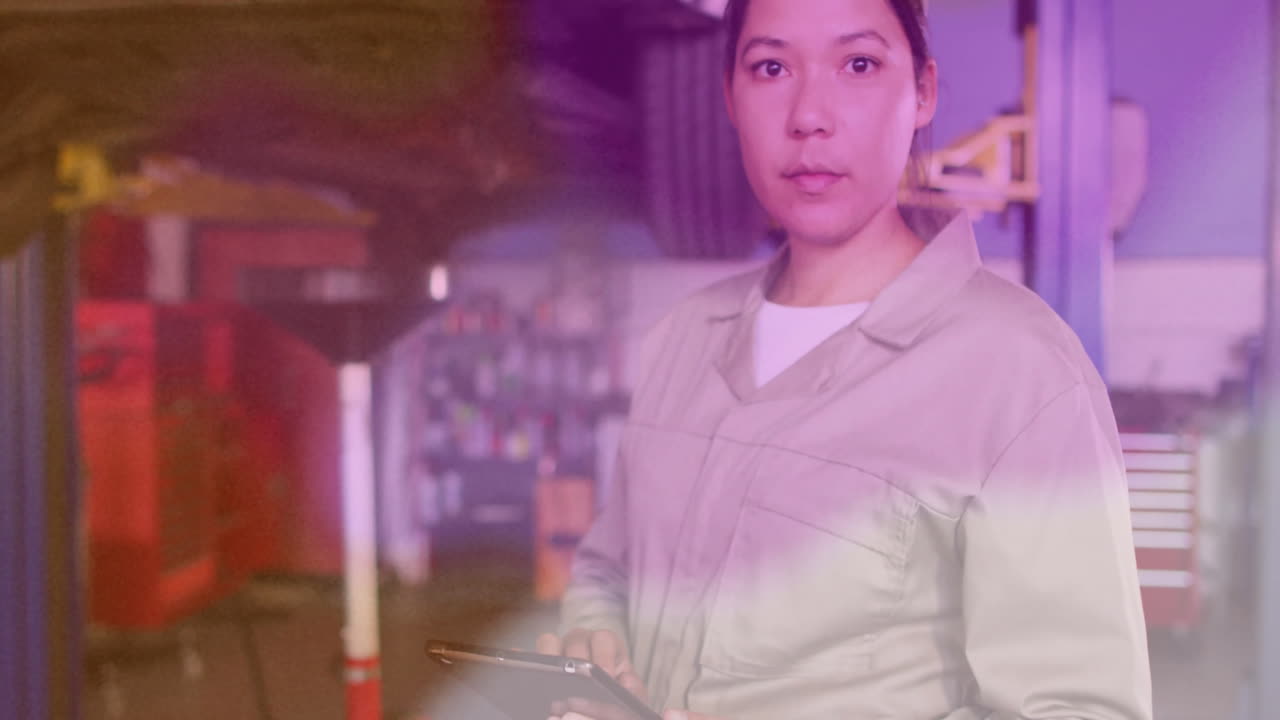 Female mechanic holding tablet in auto garage, displaying animated diagnostic overlay with graphs