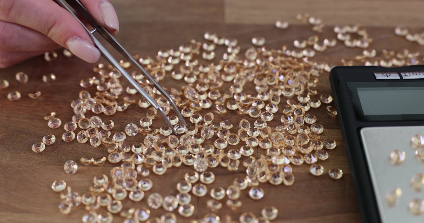 Professional jeweler takes small diamonds using tweezers