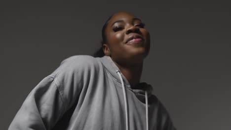 Studio-Portrait-Shot-Of-Young-Woman-Wearing-Hoodie-Dancing-With-Low-Key-Lighting-Against-Grey-Background-8