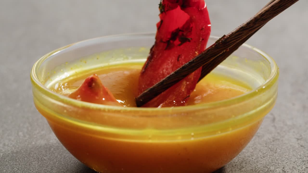 Dipping Red Food in Yellow Sauce with Chopsticks