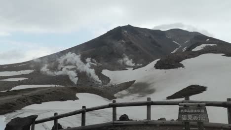 Small-people-walking-in-line-on-grand,-snowy,-foggy-mountain,-Mt