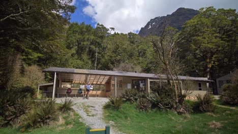 Pan,-female-hiker-takes-photos-of-mountainous-landscape,-Routeburn-Flats-Hut-New-Zealand