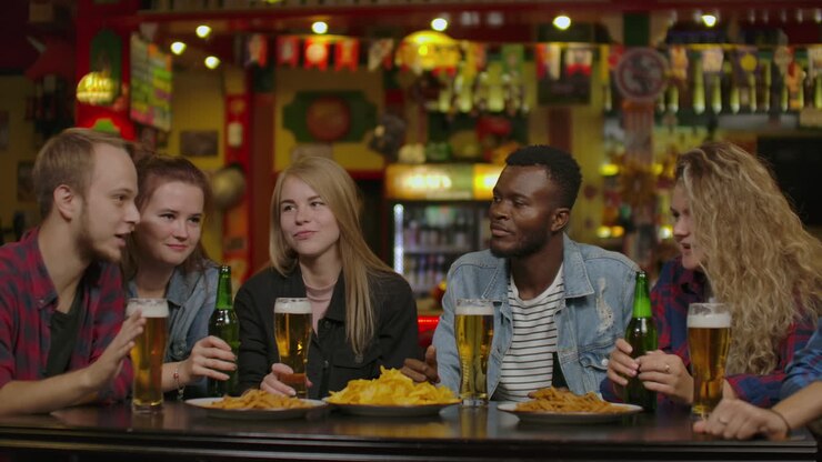 Gruppo di giovani amici che bevono e ridono in un bar.