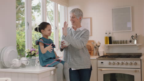 Großmutter-Gibt-Einem-Kleinen-Mädchen-In-Der-Küche-High-Five.-Oma-Feiert-Zu-Hause-Teamarbeit-Mit-Enkelin