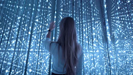 A cinematic shot of a girl interacting with the illuminated blue lights art installation at TeamLab Planets in Tokyo.