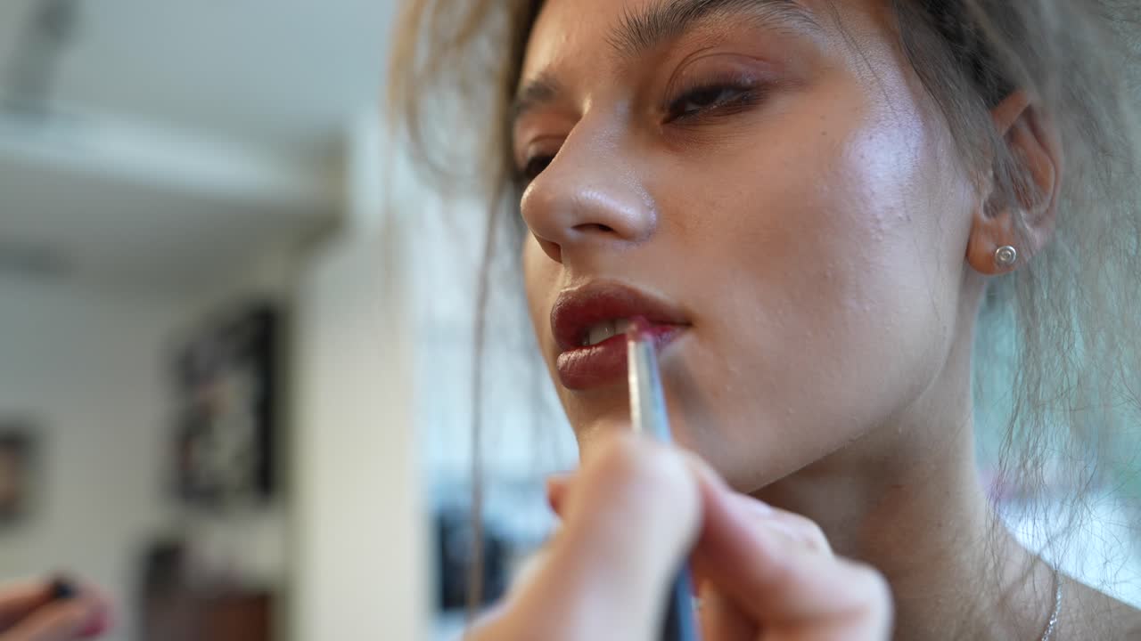 Makeup Artist Applying Lipstick to a Young Woman's Lips