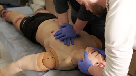 el médico táctico cubre la herida con un vendaje en el maniquí.