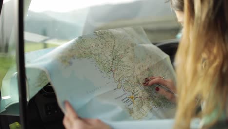 driver writing on paper map in car during trip