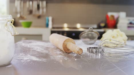 Flour-jar,-baking-equipment-and-dough-placed-on-kitchen-platform-4K-4k