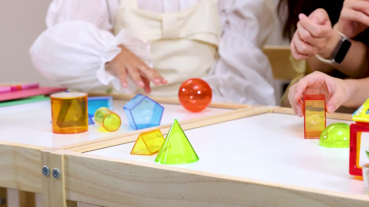 Kids and teacher interact with colorful geometric blocks on classroom table, bright lighting, static shot