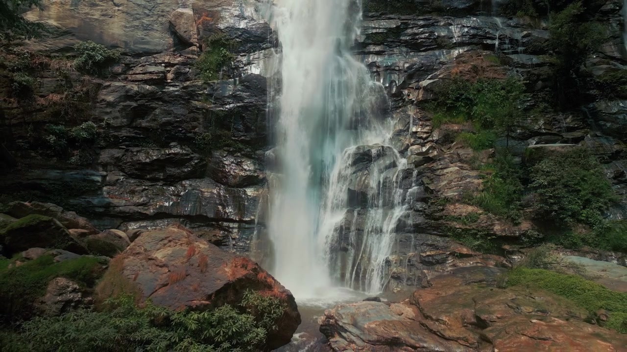 Potente cascata che scende da una scogliera rocciosa nella natura rigogliosa