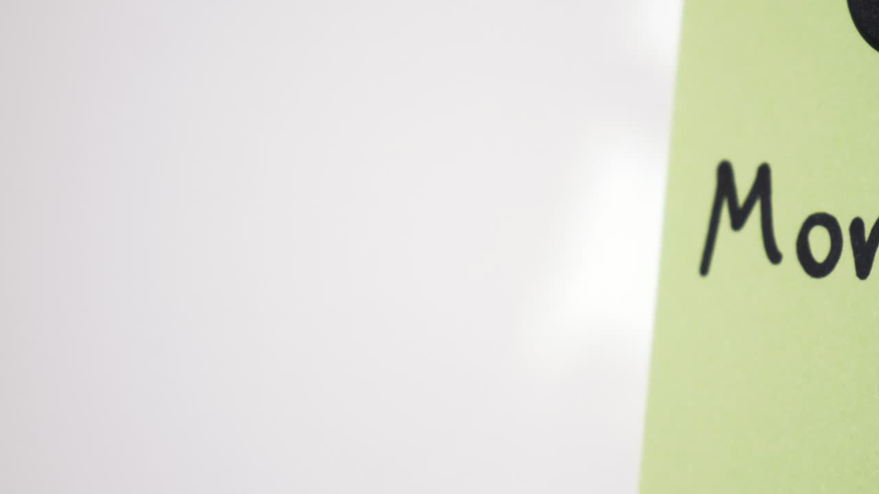 Pan reveal of Mortgage text on green note held by magnet on whiteboard with selective focus