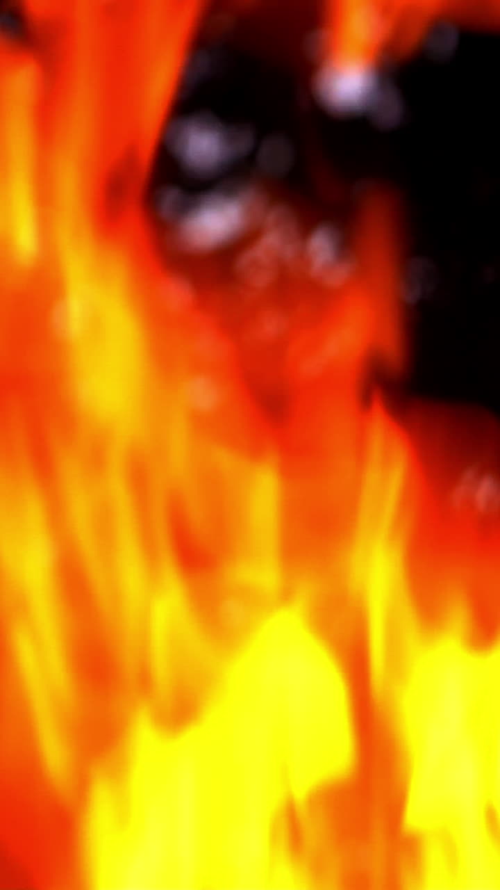 Slow motion of fire at bonfire in the dark, closeup Vertical video