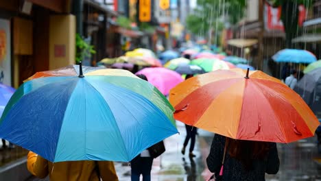 un grupo de personas caminando por una calle con paraguas en la lluvia