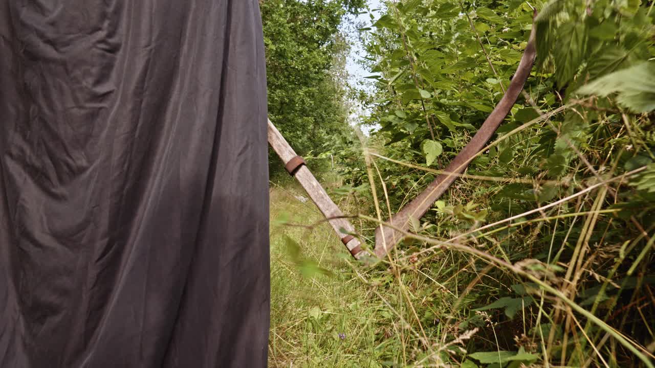 검은 망토를 입은 저승사자가 낫을 들고 있다