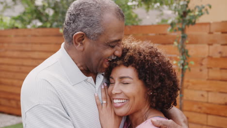 hombre negro mayor y su hija de mediana edad riendo y abrazándose al aire libre, de cerca