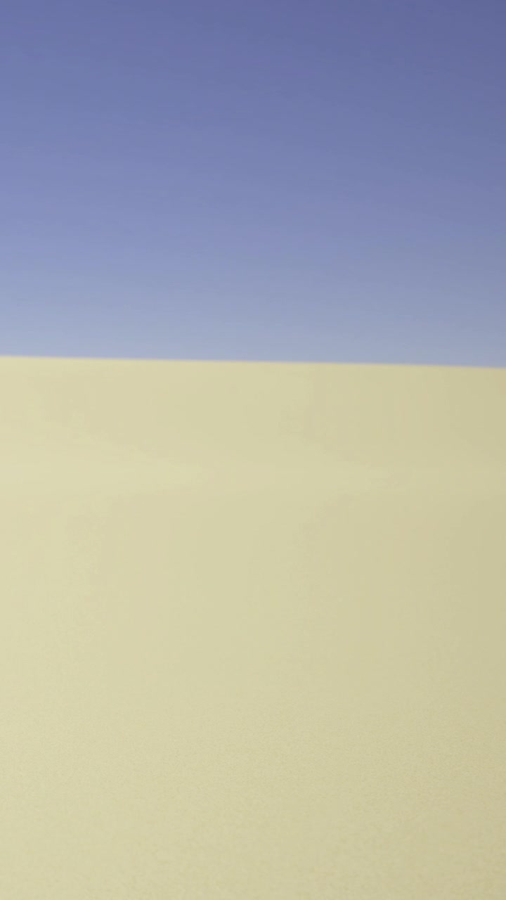 Dune di sabbia si estendono sotto un cielo sereno sotto il caldo sole pomeridiano.