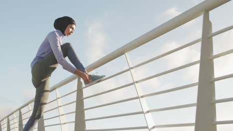 mujer con hijab escuchando música afuera atando sus cordones de zapatos