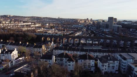 aerial view of a train on a viaduct over a suburban city