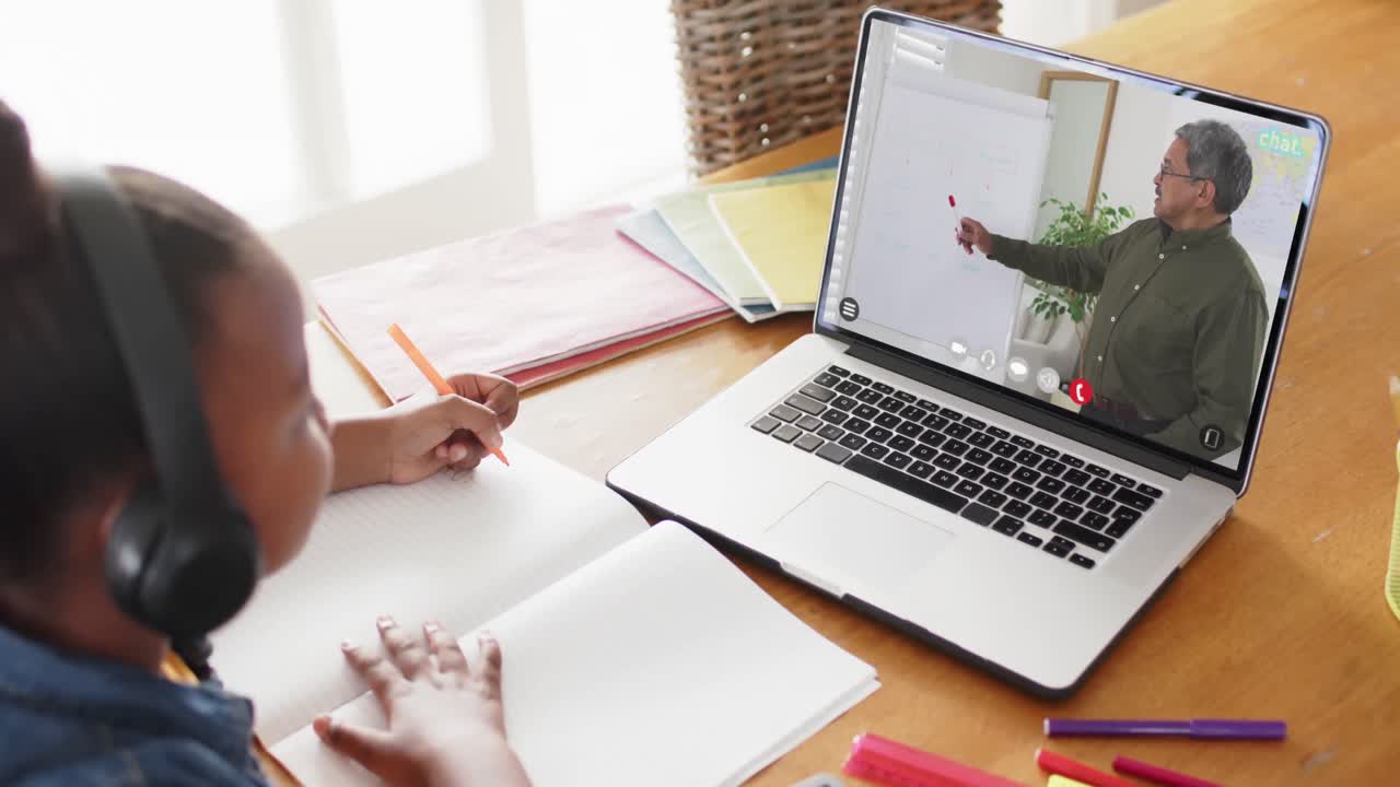 chica afroamericana usando una computadora portátil para una lección en línea con un profesor masculino biracial en la pantalla