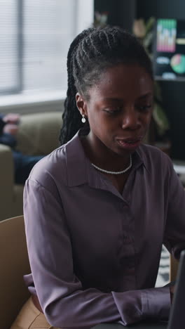 focused black woman working on laptop in office