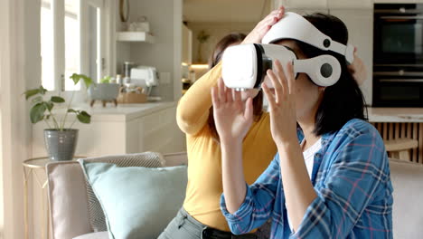Using VR headset, woman interacting with virtual environment while friend watches