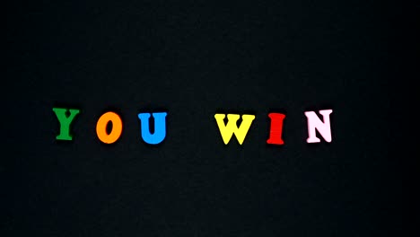 la palabra "usted gana" está formada por letras de madera multicolores. palabras coloridas en bucle.