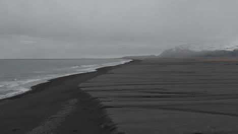 Establishing-shot-flying-along-the-vast-landscape-of-black-sand-beach