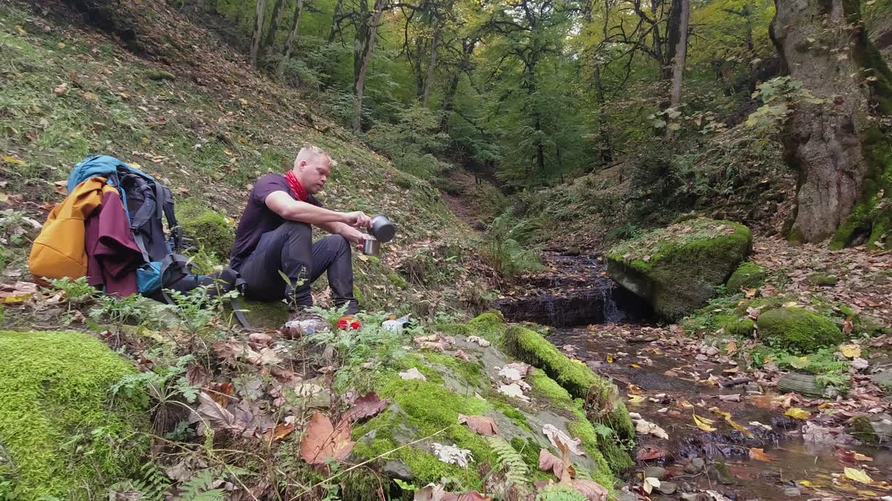 joven hierve agua caliente para el té por el arroyo del bosque verde